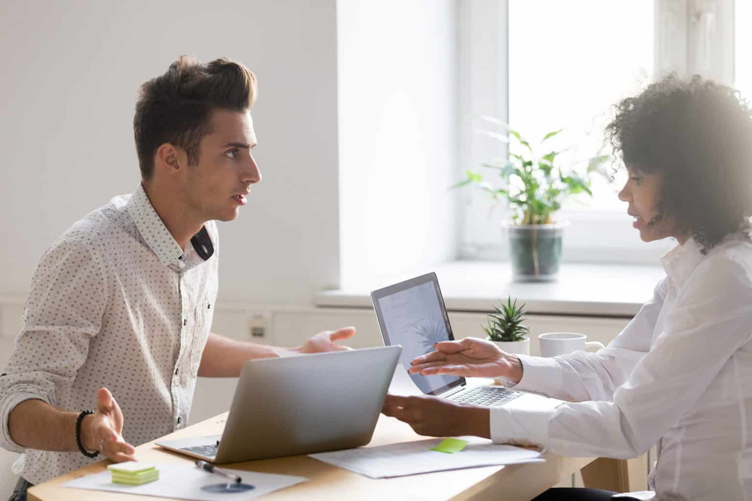 two employees sat across from each other experience a conflict at work