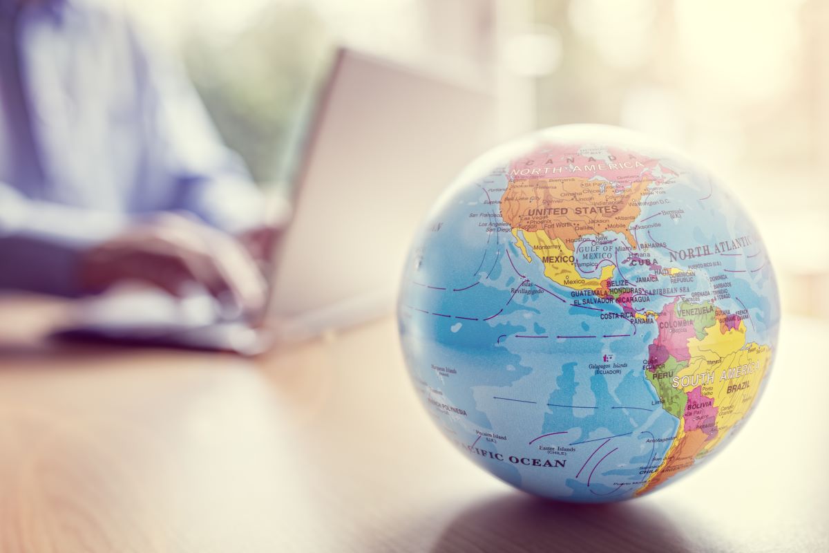 How to Obtain a Sponsor License - world globe is in the foreground, in the blurred background is a businessman working on a laptop
