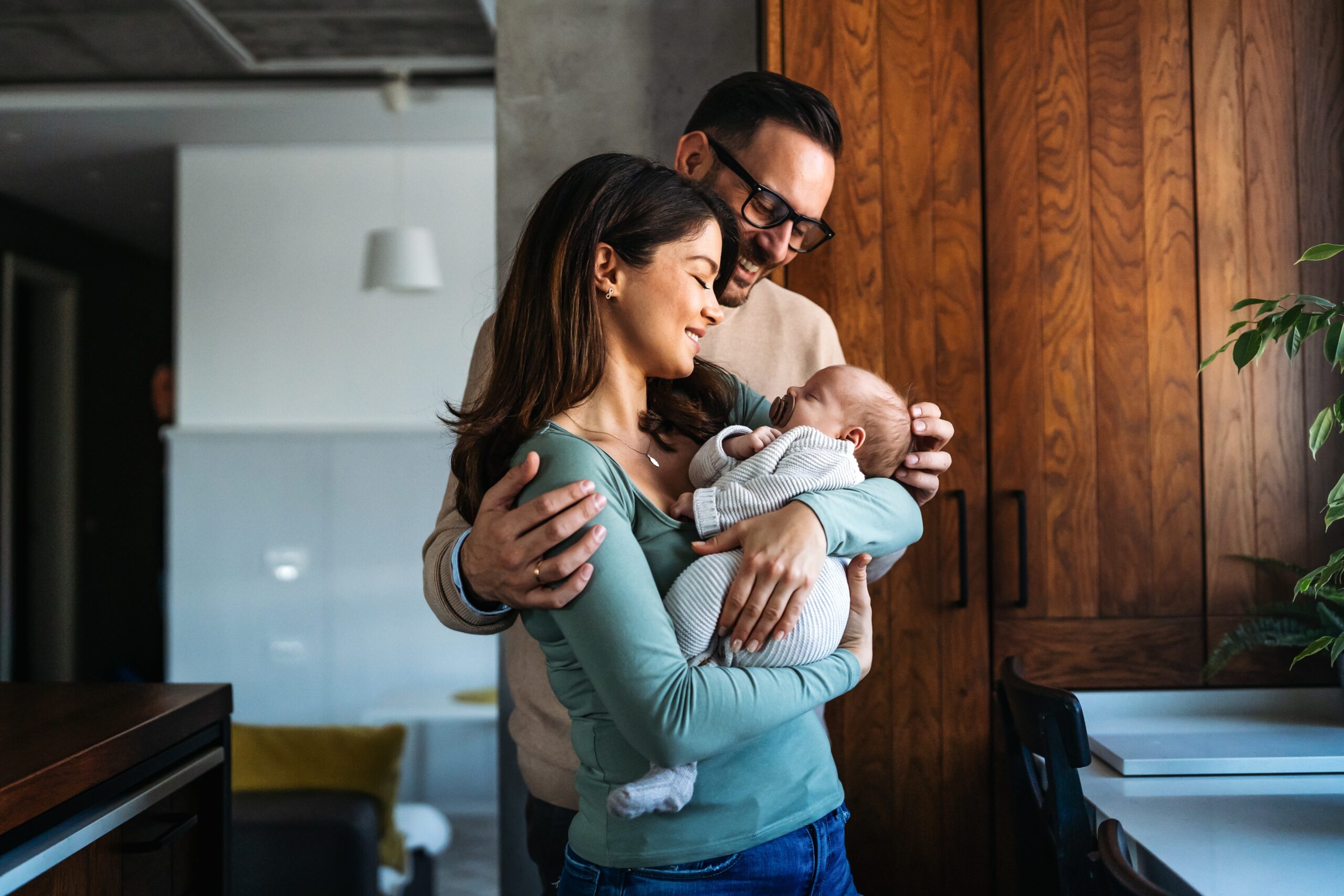 A man and woman holding a baby. Changes to family leave and pay in 2025.