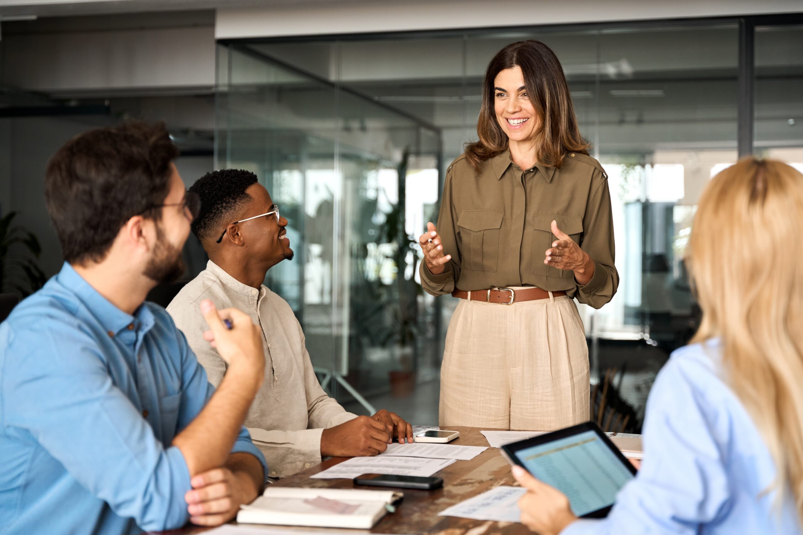 A woman standing in front of a group of people. Celebrating International Women's Day in the workplace.