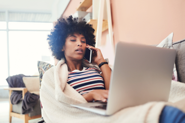 Person on phone with laptop calling in sick with work. UK Sick pay changes.